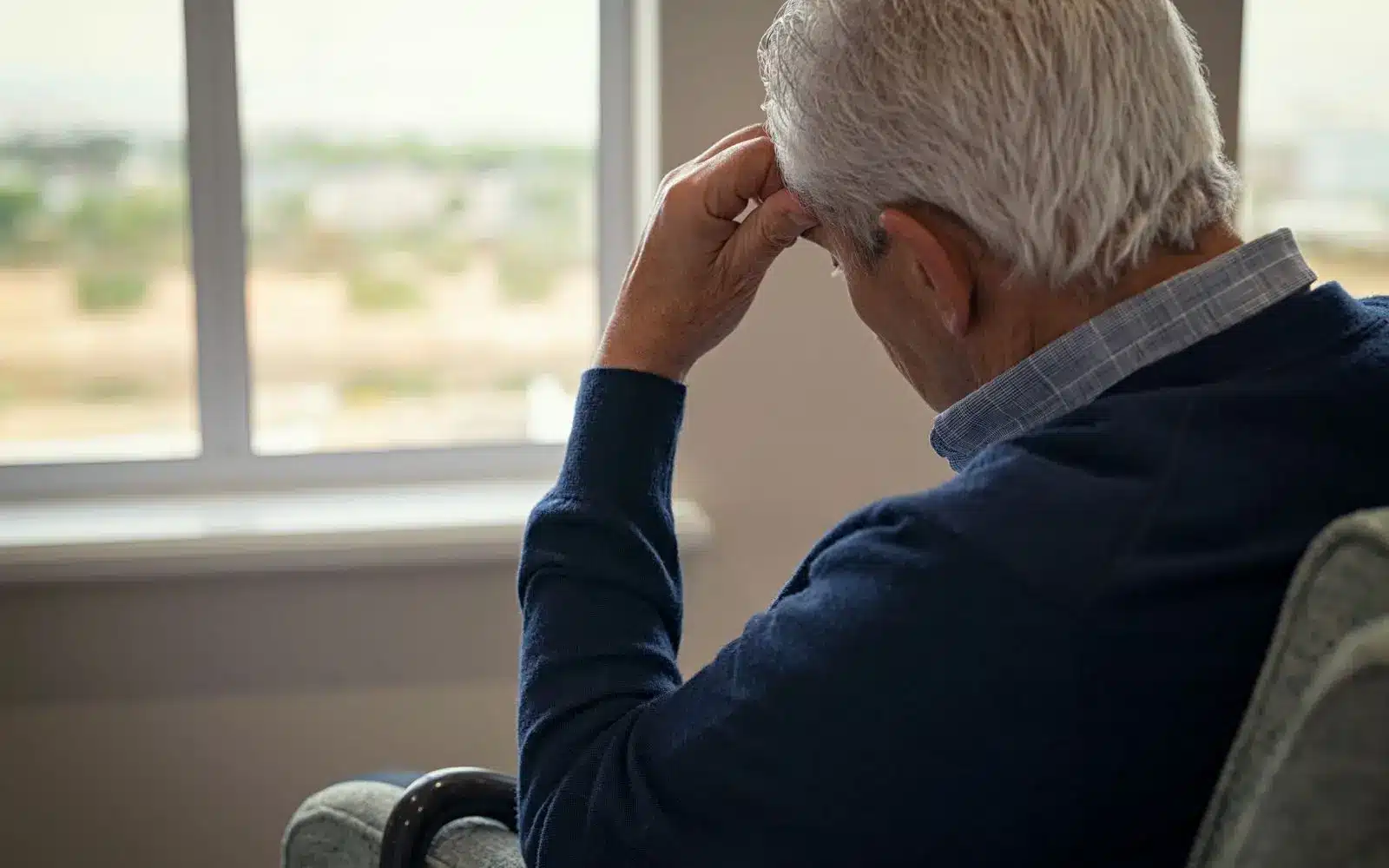 upset elder looking outside of the window