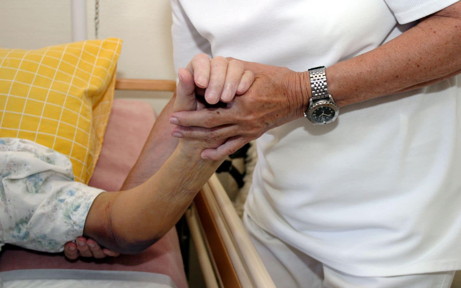 person holding hands with elder who has bedsore from stay in nursing home