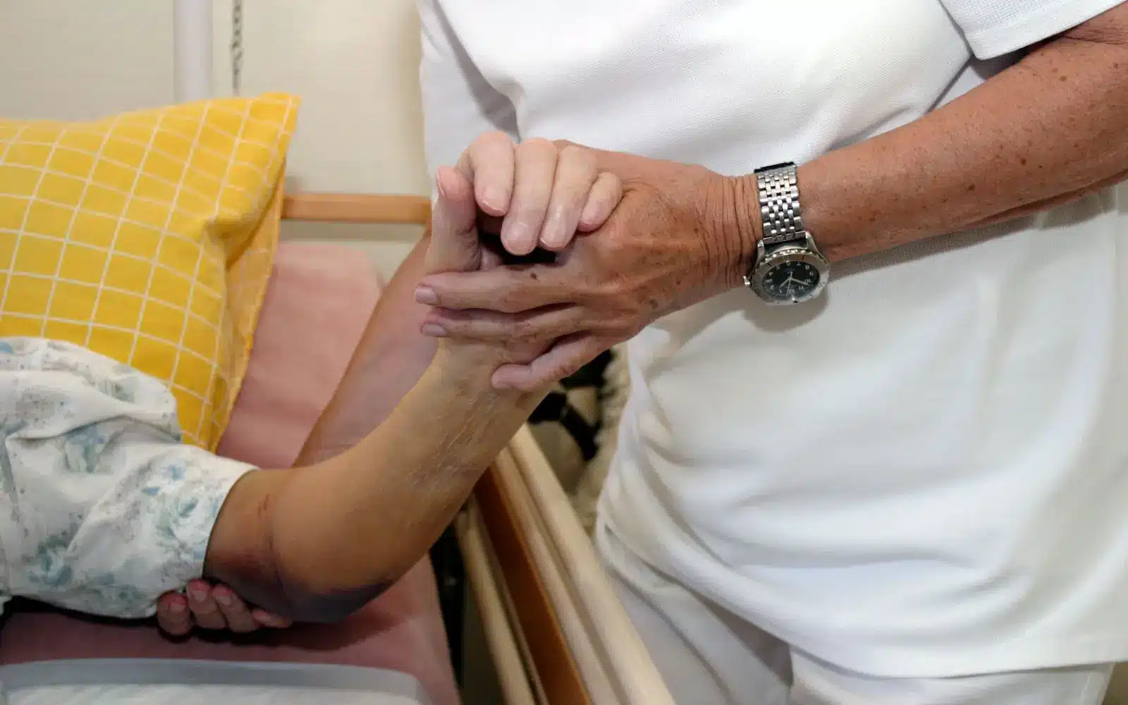 person holding hands with elder who has bedsore from stay in nursing home