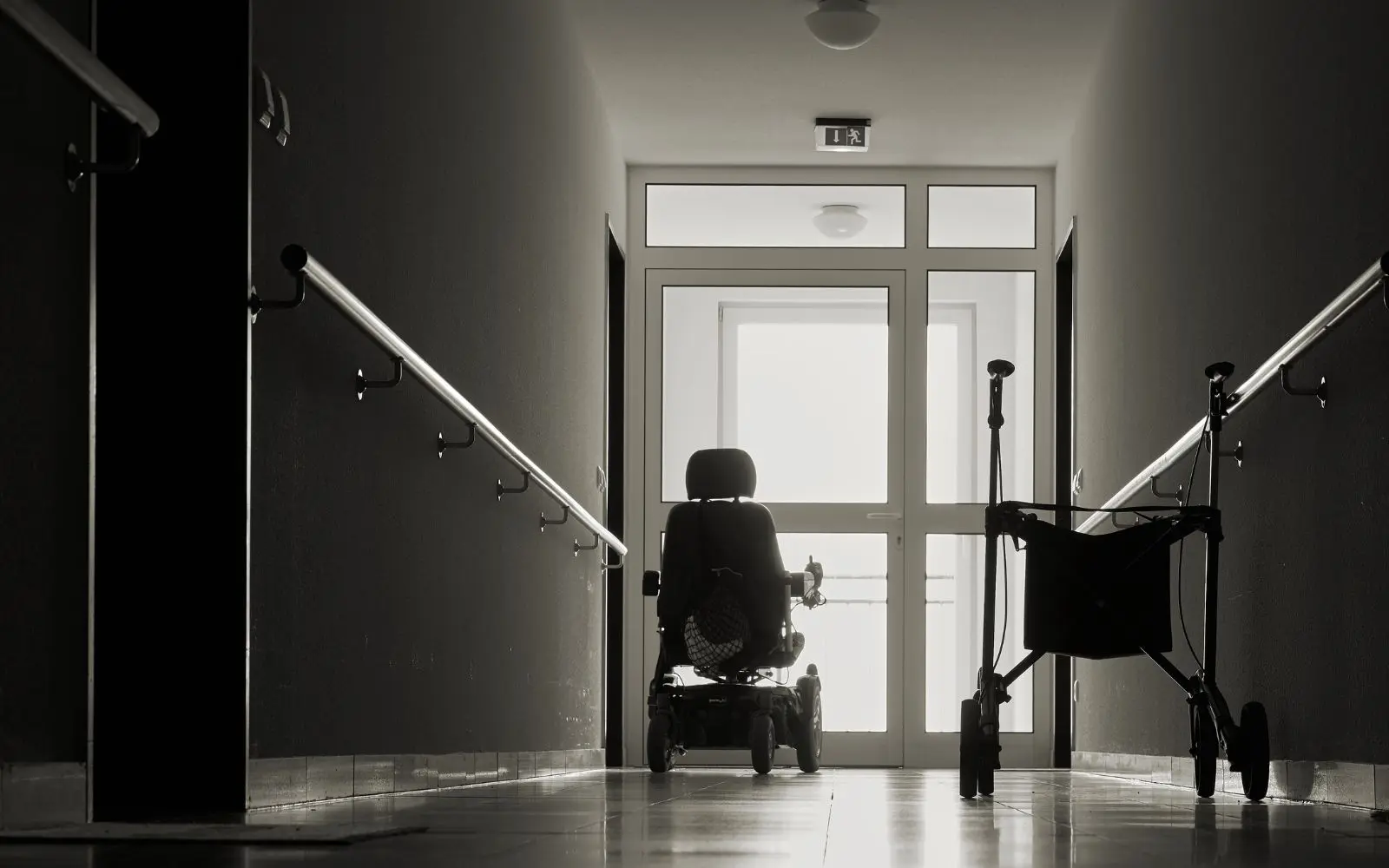 black and white image of vacant wheelchair sitting in the hallway of nursing home